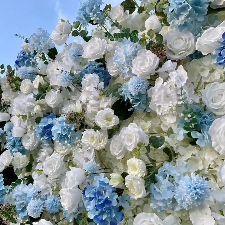 Serene floral wall with white and light blue flowers, perfect for weddings and events.