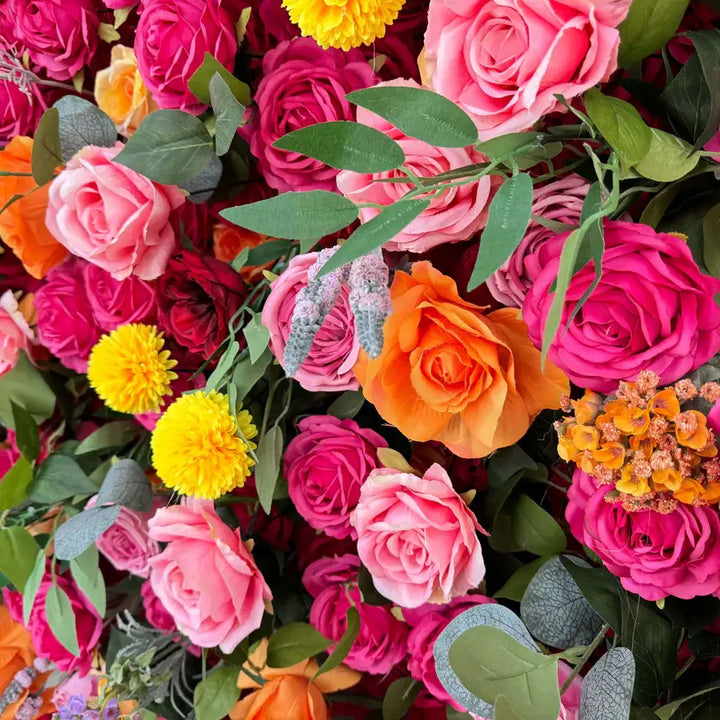 Close-up of colorful roses, marigolds, and green foliage on vibrant flower wall.