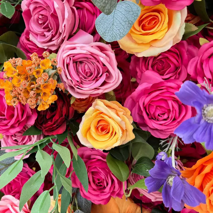 Detailed view of peach and pink roses with violet and yellow accents.
