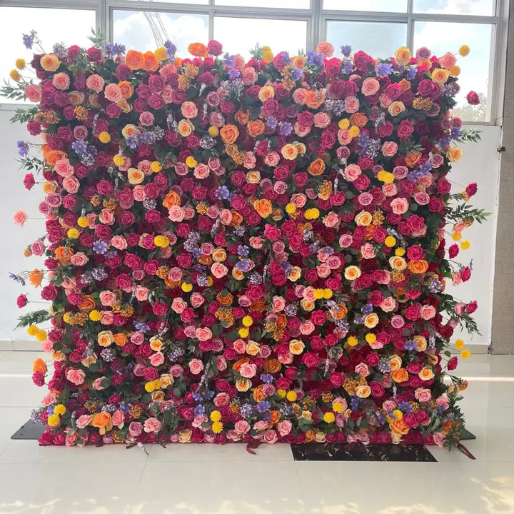 Close-up of colorful roses, marigolds, and green foliage on vibrant flower wall.