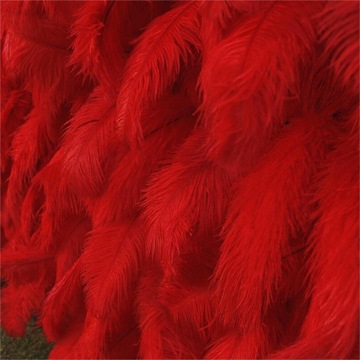 Vibrant red feather flower wall backdrop against a white wall for weddings and events