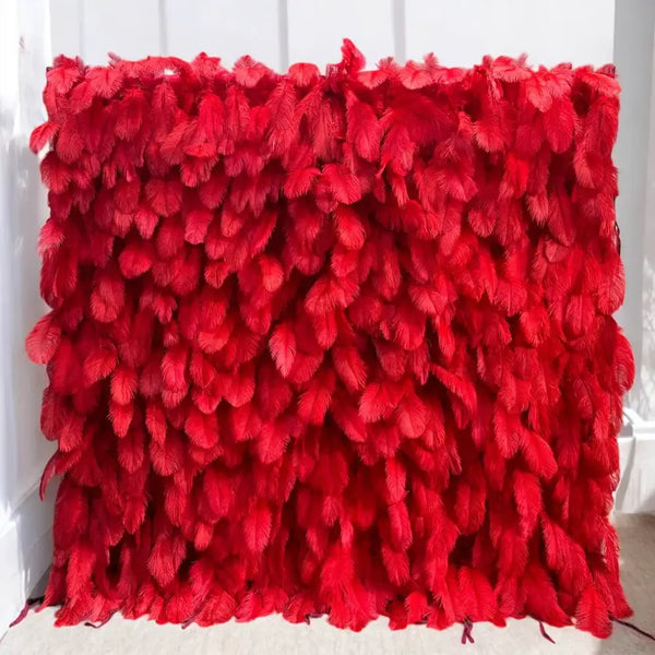 Vibrant red feather flower wall backdrop against a white wall for weddings and events
