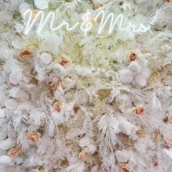 Close-up of white roses and soft champagne accents on luxury flower wall.