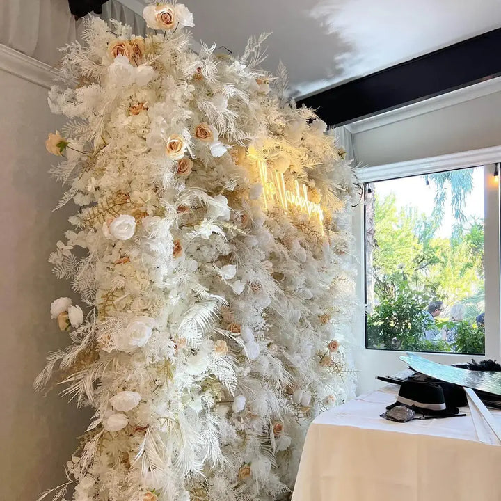 Floral wall backdrop behind elegant reception table with ambient lighting.