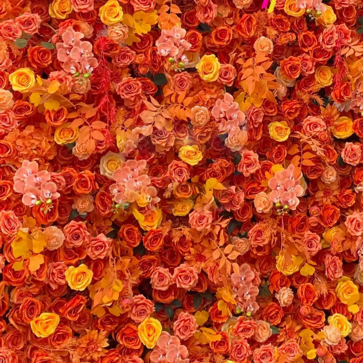 Close-up of orange roses, yellow florals, and peach orchids in the decorative flower wall
