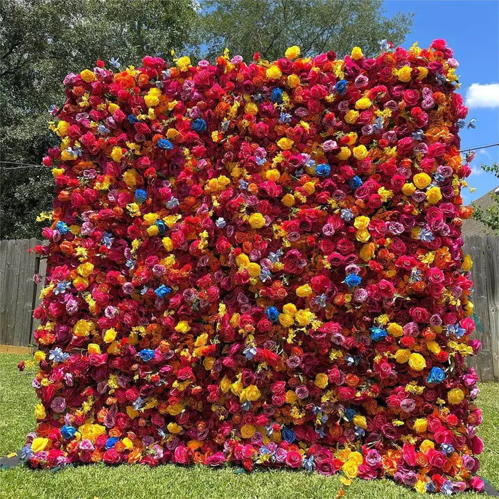 Full frontal view of bold, rainbow-toned decorative flower wall on green grass