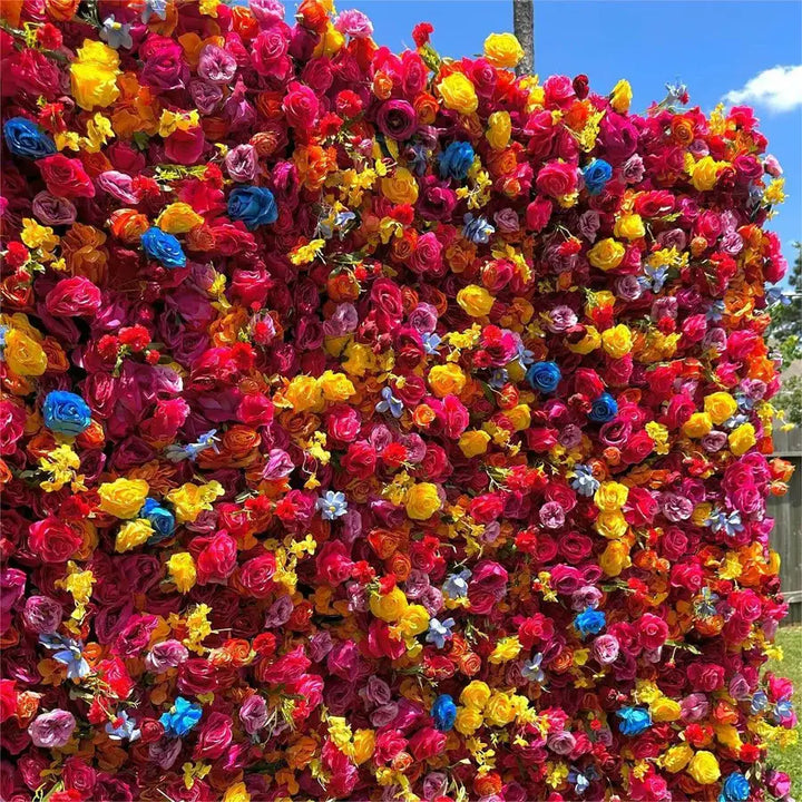 Full frontal view of bold, rainbow-toned decorative flower wall on green grass