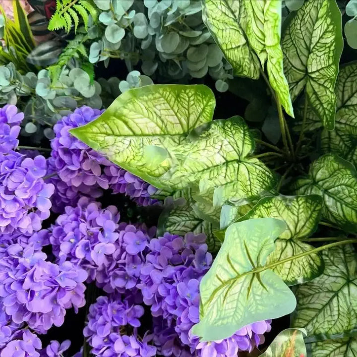 Close-up of purple and green floral arrangements in a decorative flower wall.