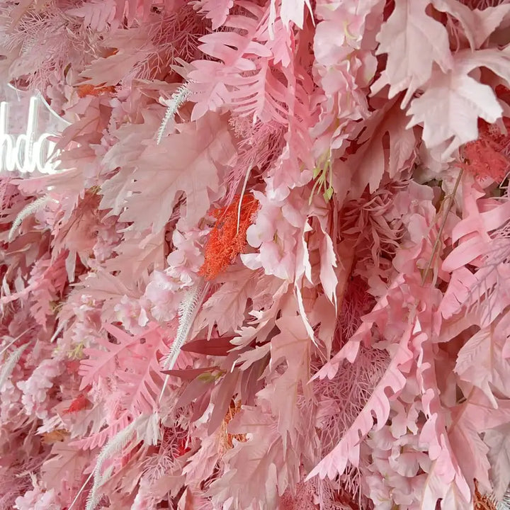 Close-up of faux fern leaves in blush and peach hues in decorative backdrop