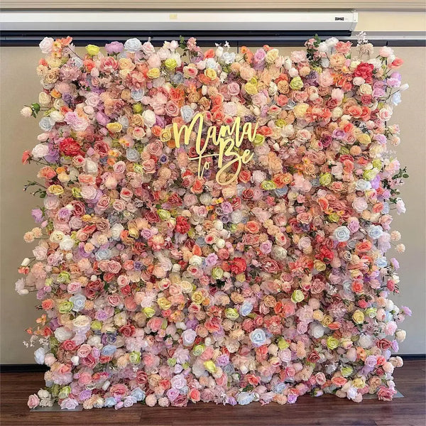 Pastel floral wall backdrop with “Mama To Be” sign featuring blush roses and ranunculus.
