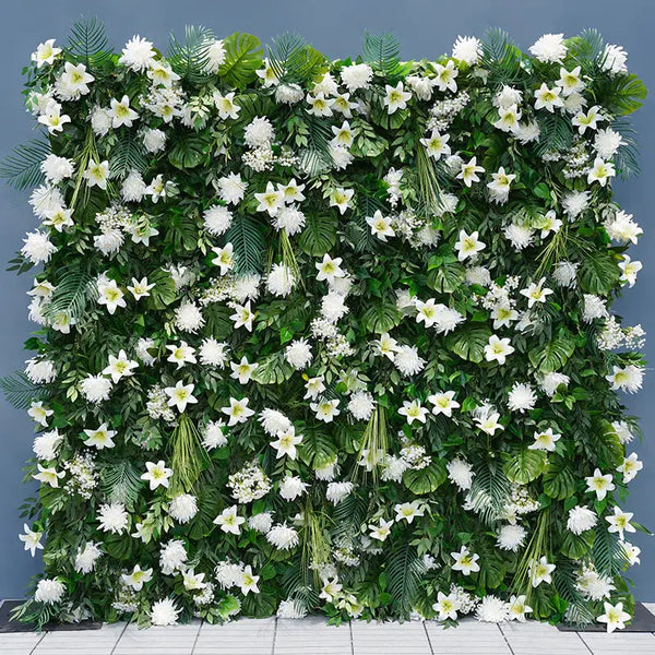 Green and white flower wall backdrop with lilies and tropical leaves.