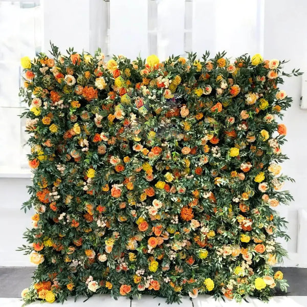 Radiant orange and yellow floral wall backdrop at an indoor event, featuring vibrant blooms and lush foliage.