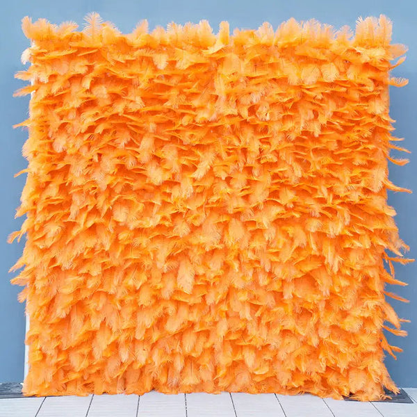 Bright orange feather flower wall backdrop set against a blue wall.