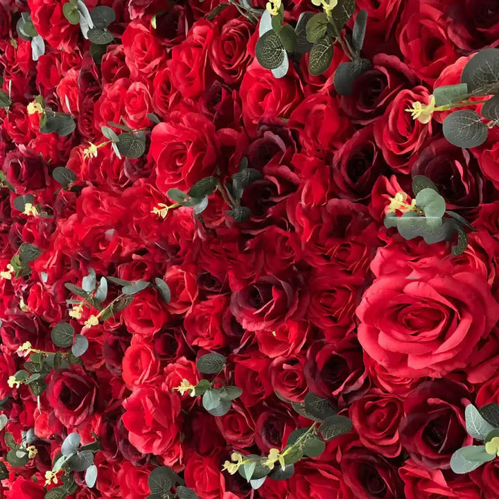 Red rose flower wall backdrop with dense blooms and green accents.
