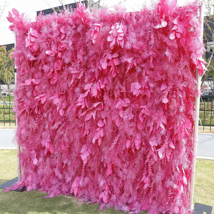Close-up of decorative flower wall with layered pink leaves and pine fronds