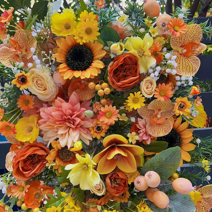 Close-up of a floral wall backdrop featuring sunflowers, yellow roses, and vibrant orange blooms for event decoration.