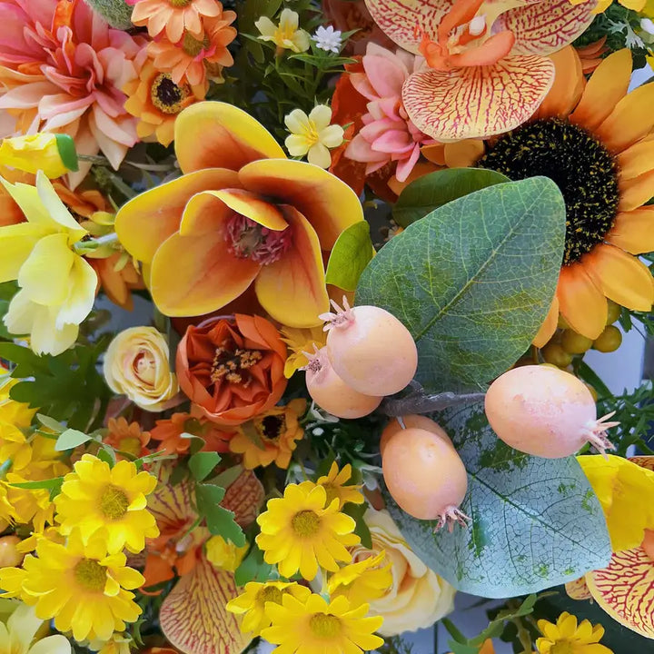 Close-up of a floral wall backdrop featuring sunflowers, yellow roses, and vibrant orange blooms for event decoration.