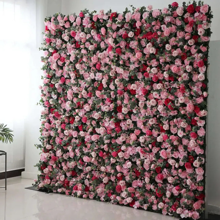 Close-up of a lush floral wall backdrop featuring a variety of roses in pink, red, and white, perfect for event decorations.