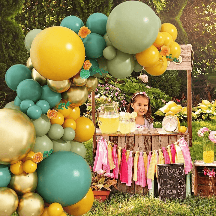 Balloon garland in yellow, green, and gold with floral decorations for baby shower celebration
