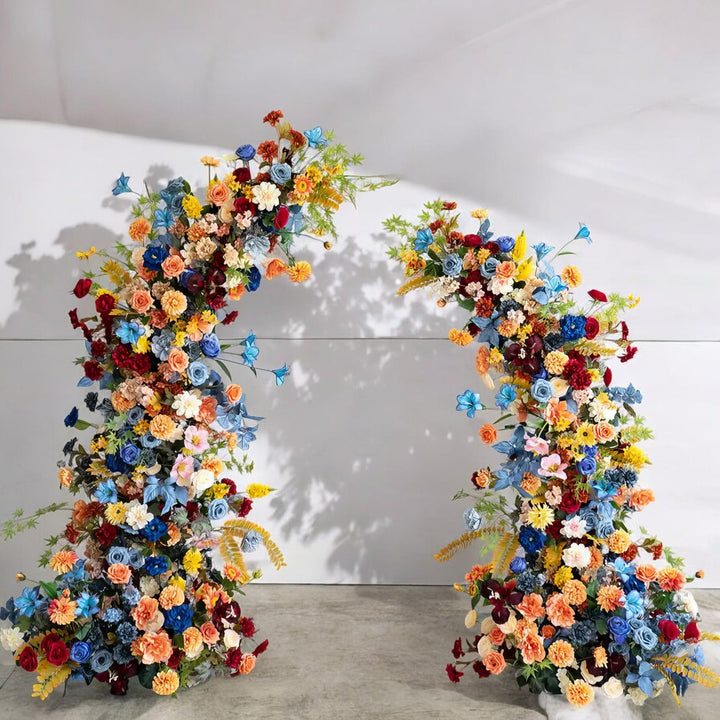 Colorful floral arch with a vibrant mix of blue, red, yellow, and peach flowers, ideal for adding a lively and unique touch to weddings and special events.