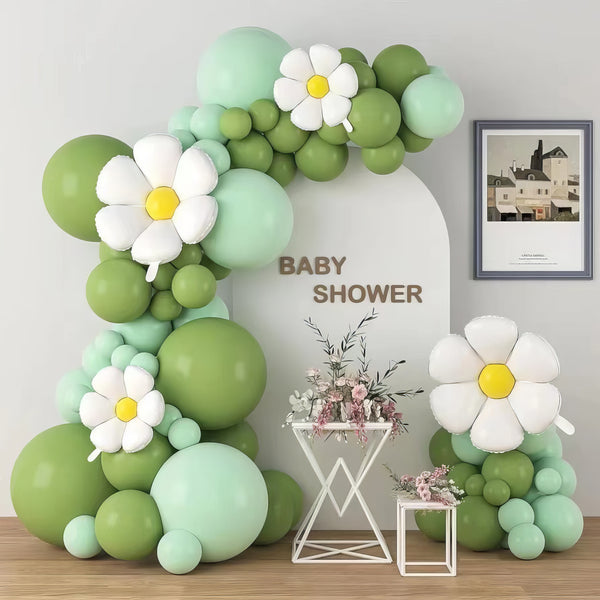 Pastel green and white balloon arch with daisy accents for baby shower
