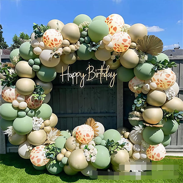 Rustic green and gold balloon arch with botanical accents for outdoor birthday party
