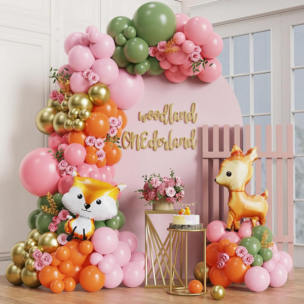 Woodland-themed balloon arch with pink, green, and orange balloons for first birthday
