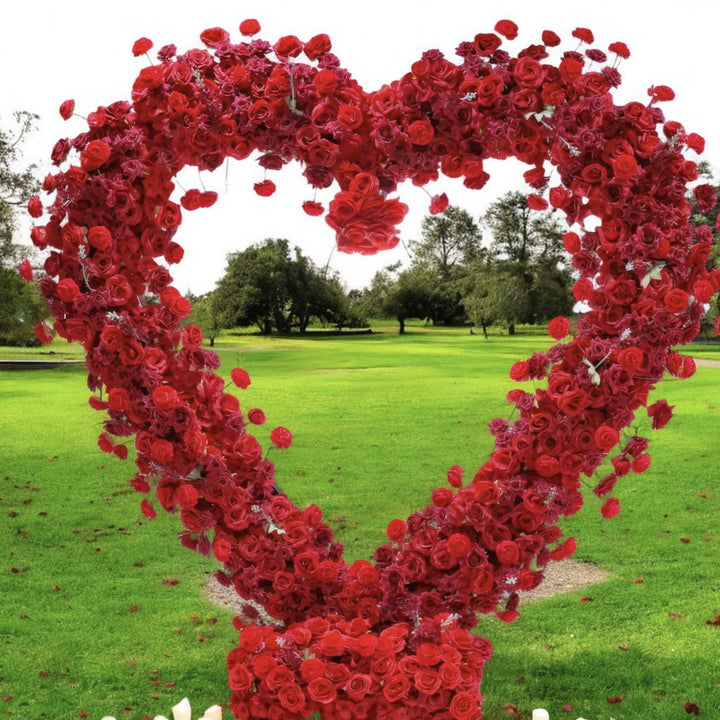 Romantic heart-shaped red rose floral backdrop with scattered candles and petals, ideal for creating an intimate setting at weddings or proposals.