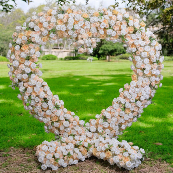 Heart-shaped floral arch with white and blush roses set against a lush green park background, perfect for wedding decor and outdoor events.