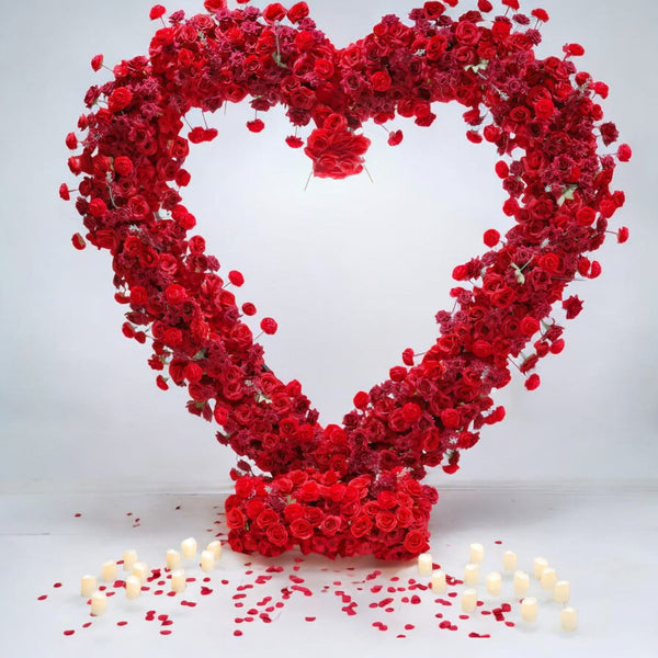 Romantic heart-shaped red rose floral backdrop with scattered candles and petals, ideal for creating an intimate setting at weddings or proposals.