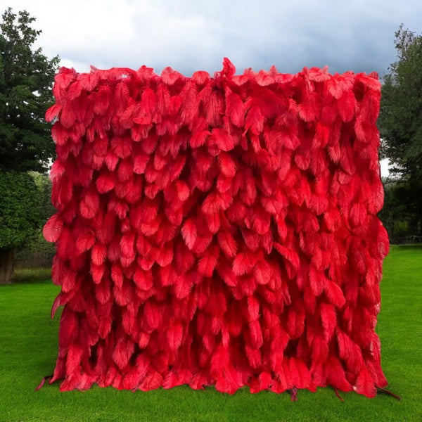 Vibrant red feather flower wall backdrop against a white wall for weddings and events