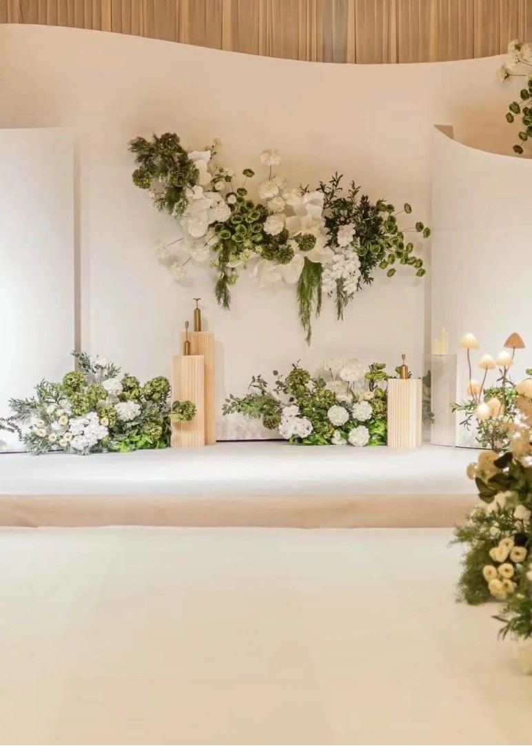 Elegant wedding aisle with floral arrangements and candle holders, leading to a beautifully designed backdrop with personalized text, perfect for a luxurious celebration.